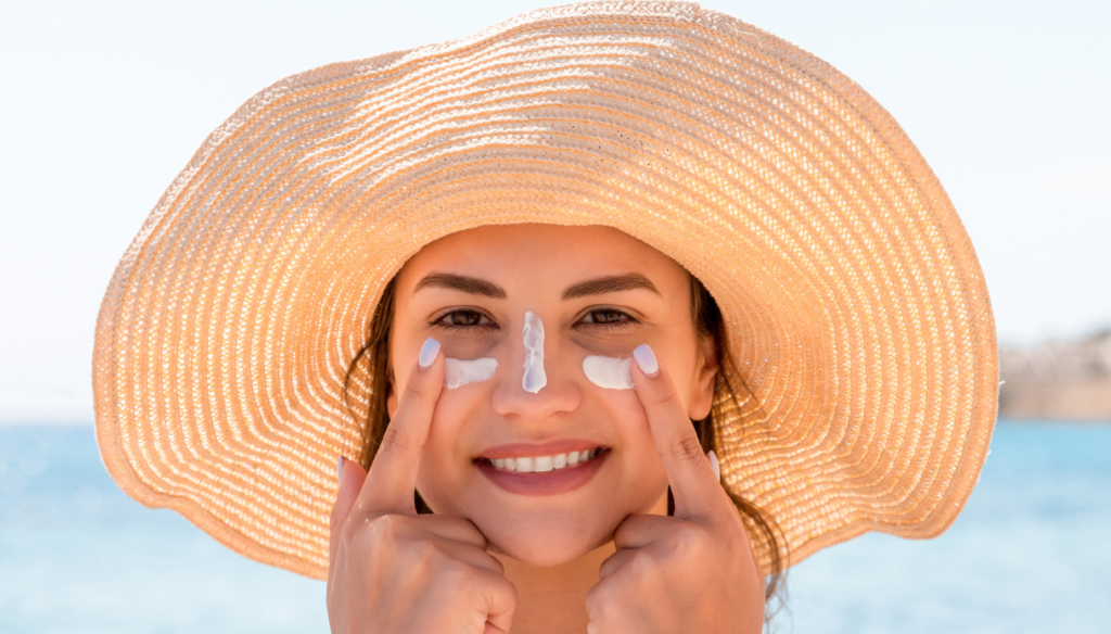 Girl with sunscreen on the face at the beach