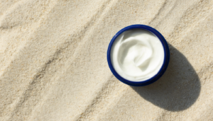 white cream in cosmetics bottle on the sand